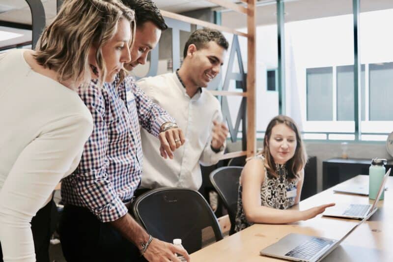 Team members discussing and working on a computer presentation